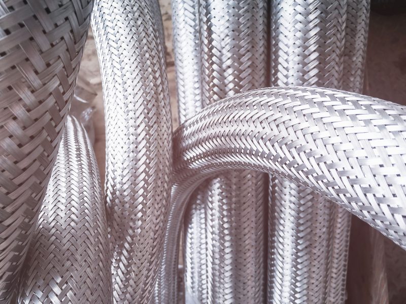 Long,Metal,Flexible,Compensator,Pipes,Metal,Texture,Closeup,With,Lens Long metal flexible compensator pipes metal texture closeup with lens flare. Selective focus. White metal industrial construction.